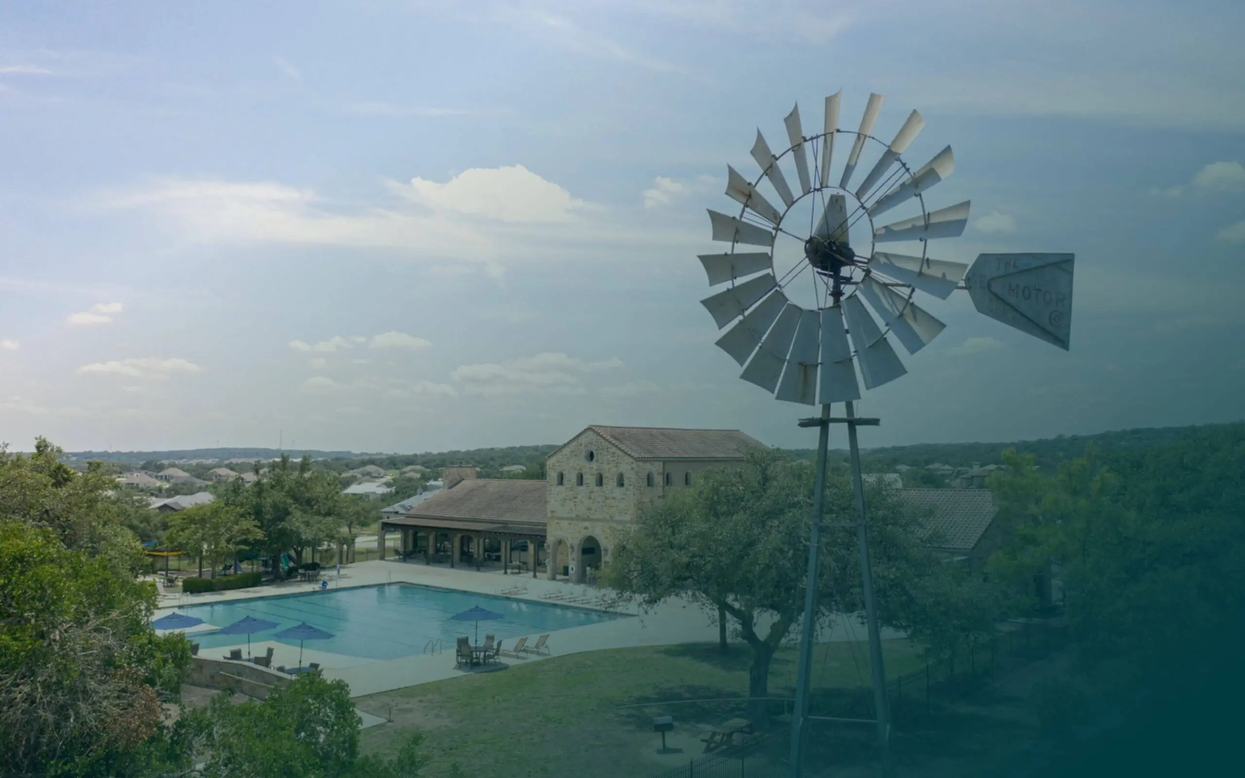 A windmill in front of a swimming pool.