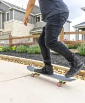 A man riding a skateboard in front of a house.