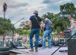 A group of musicians on stage at an outdoor concert.