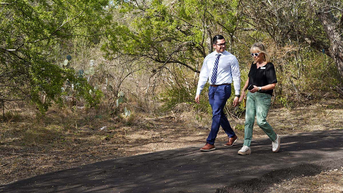 A man and woman walking down a path in the woods.
