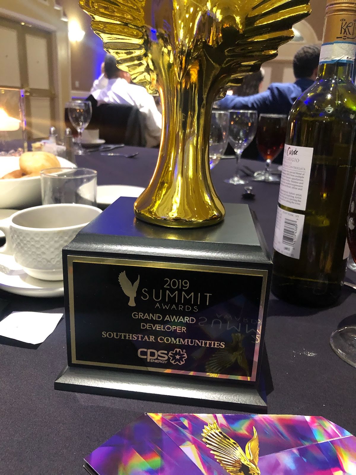 A gold Summit Awards trophy engraved with "Grand Award Developer" and with a golden eagle on it sits on a table.